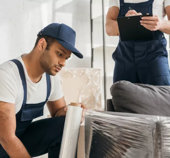Movers wrapping a sofa